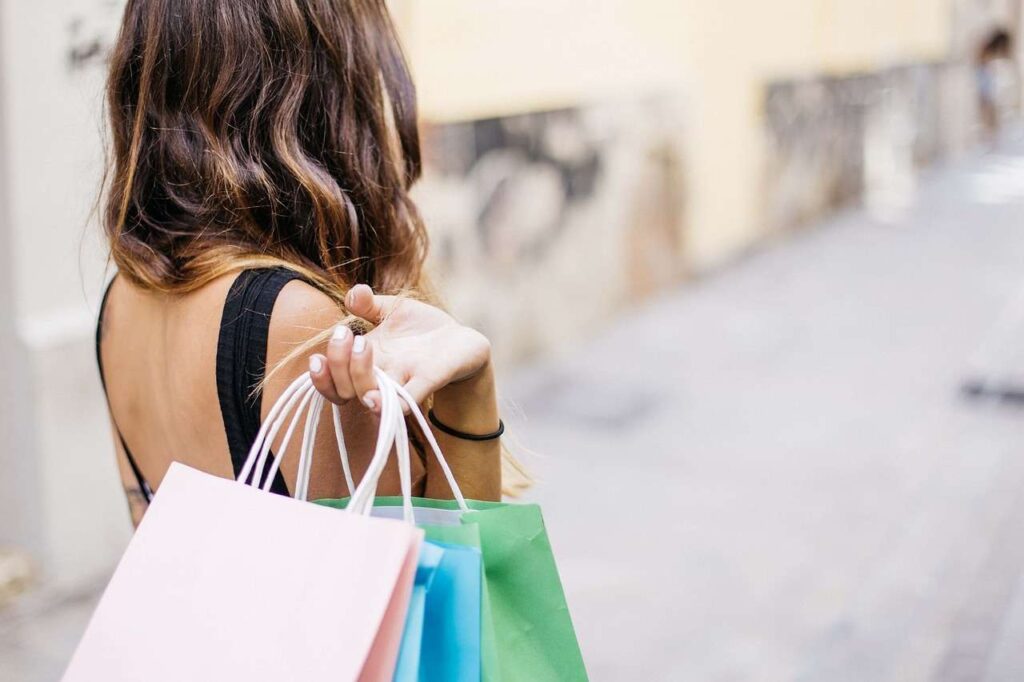 une femme tenant des sacs de courses derrière son dos.