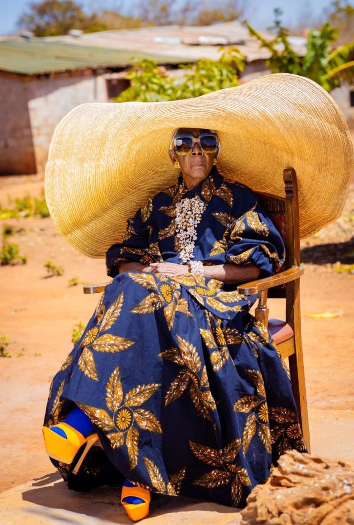 Margret Chola dans un grand chapeau et une robe