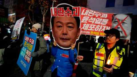 Un manifestant tient une pancarte indiquant : « Arrêtez Yoon Suk Yeol »